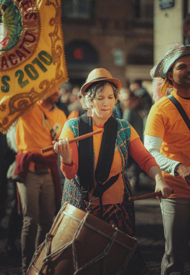 Colorful street parade featuring drummers and vibrant costumes, creating a lively festive atmosphere.